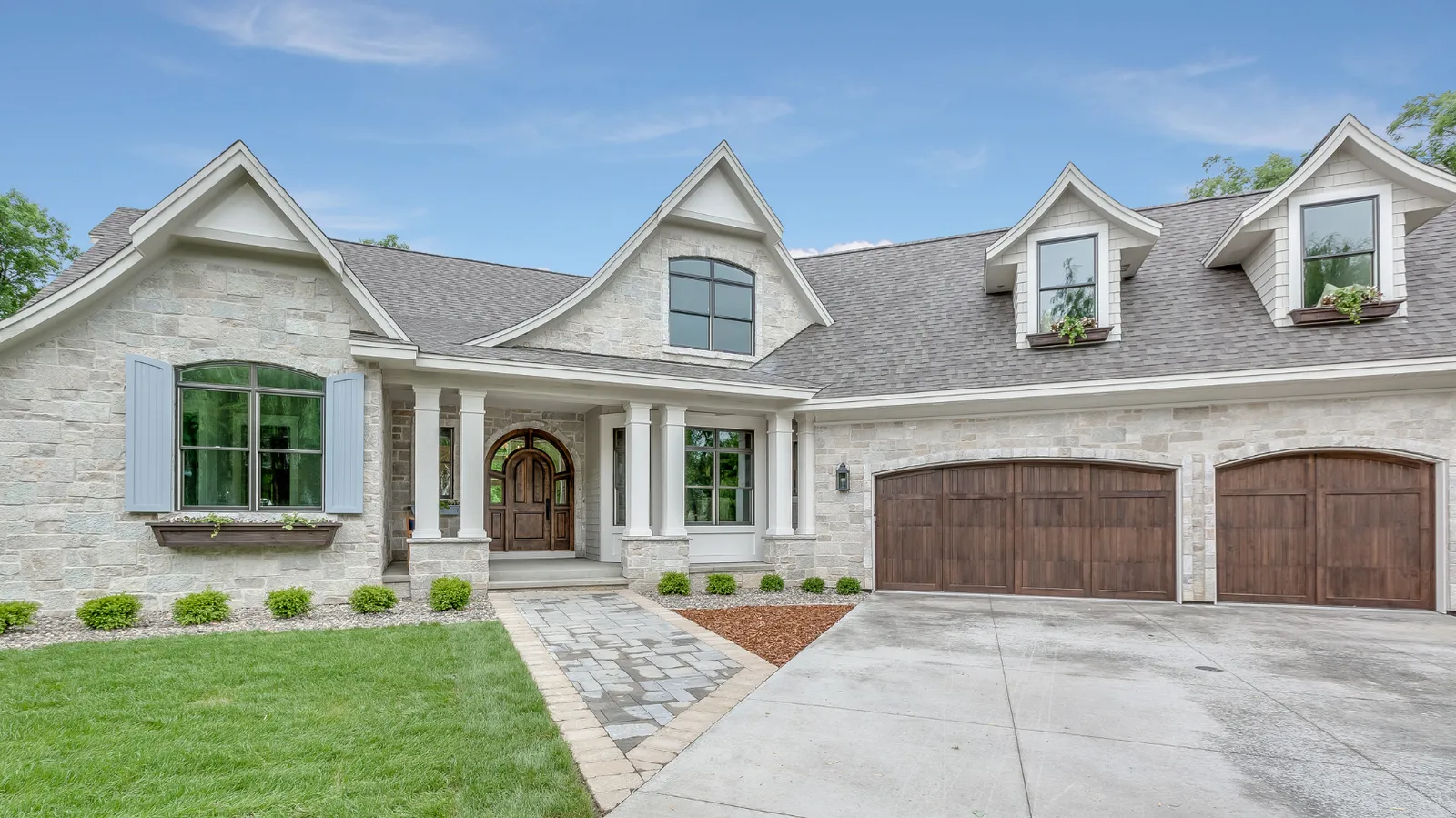 Light stone home with blue shutters and gray architectural shingle roof