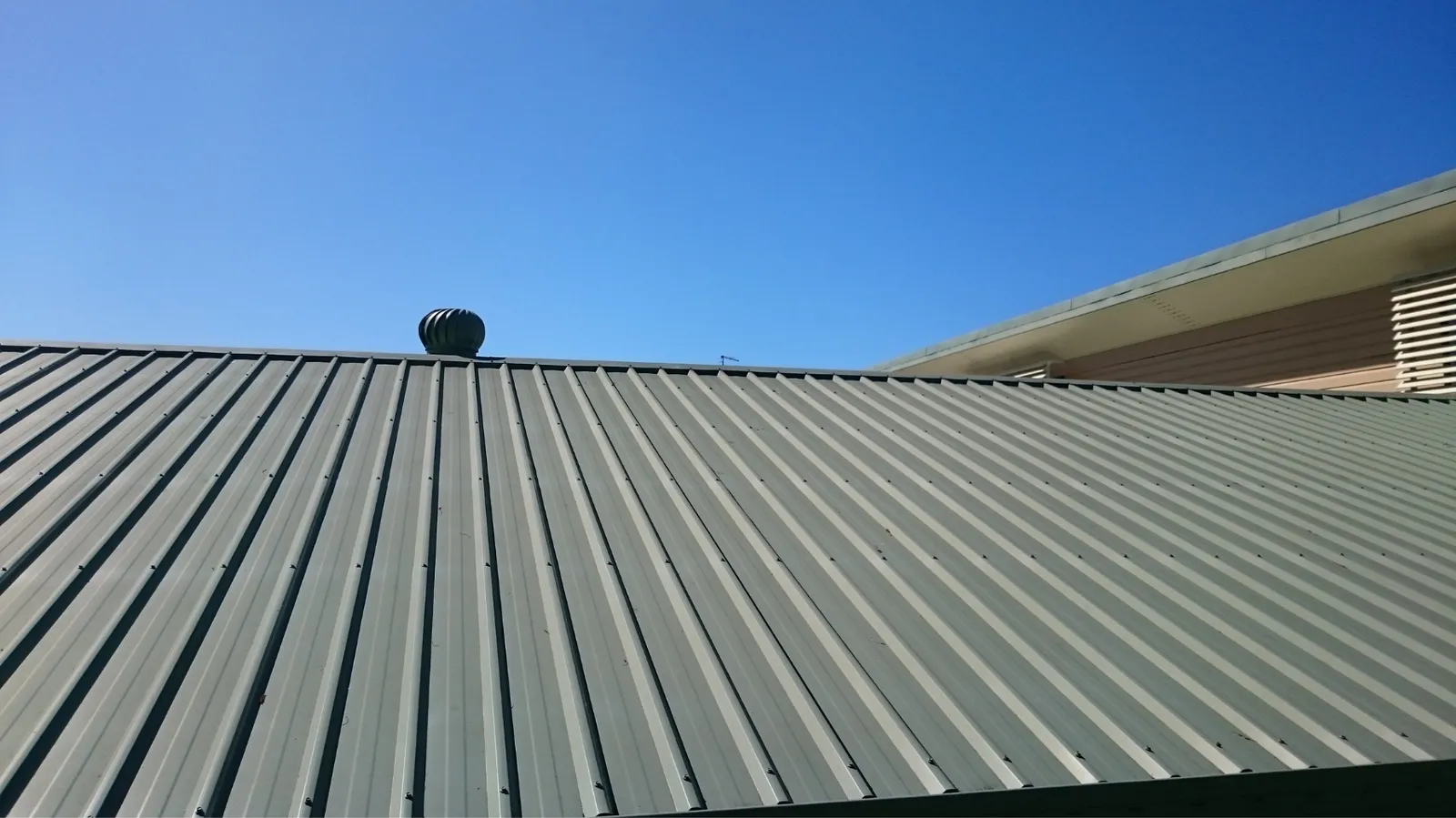 Turbine vent on a corrugated metal roof under clear blue sky